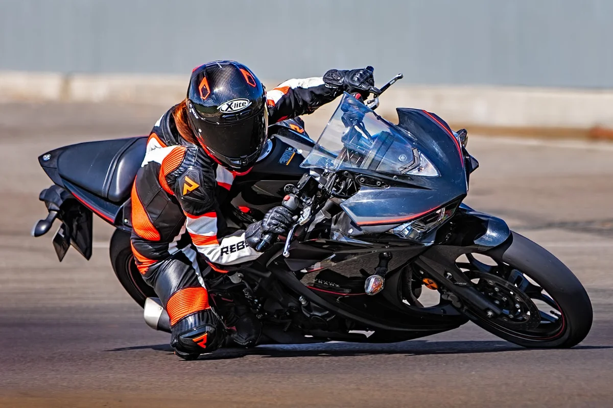 Motociclistă în echipament de protecție înclinată într-un viraj strâns pe circuit